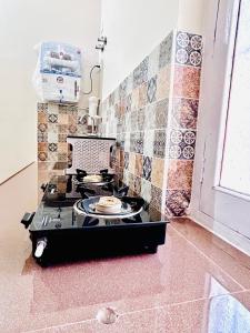 a stove top in a kitchen with tiles on the wall at Gooseberry Garden in Ayodhya