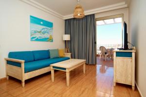 a living room with a blue couch and a tv at Balcon del Mar in Puerto Rico de Gran Canaria