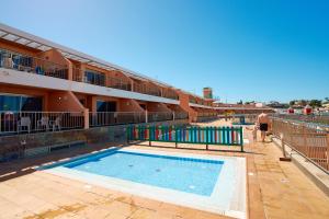 a man walking by a swimming pool next to a building at Balcon del Mar in Puerto Rico de Gran Canaria