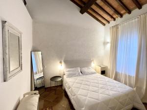 a bedroom with a white bed and a window at Villa ideale per riunioni familiari nella pace della campagna cortonese in Valiano +34 photos
