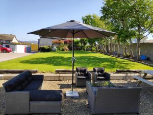 a patio with two couches and an umbrella at Fairy Bridge Lodge in Bundoran