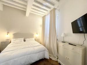 a white bedroom with a bed and a television at Villa ideale per riunioni familiari nella pace della campagna cortonese in Valiano