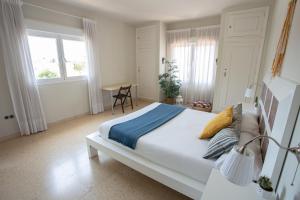 a white bedroom with a large bed and a table at BBTK Eco-Hostel in Málaga