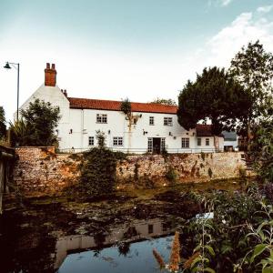 a large white building behind a stone wall next to a river at The White Hart in Brigg