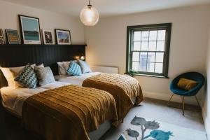 a bedroom with two beds and a chair and a window at The White Hart in Brigg