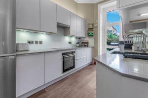 a large kitchen with white cabinets and a window at Stylish Elegance in City's Heart in Edinburgh