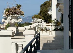 a white building with a fence and some plants at Elegant Sea View Retreat in Historic Villa with Pool in Bordighera