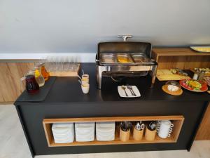 a kitchen with a counter with plates and utensils at Hotel Nenufar Premium in Kościan