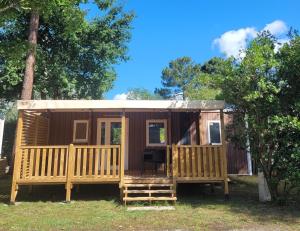 une petite cabine avec une terrasse couverte et une terrasse dans l'établissement CAMPING LES OURMES, à Hourtin