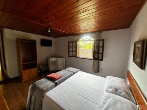 a bedroom with a bed in a room with a window at Pousada Melodia in Nova Friburgo