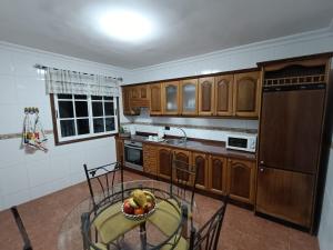 una cocina con armarios de madera y un bol de fruta en una mesa en Rincón de Joel Habitación con baño privado en La Orotava