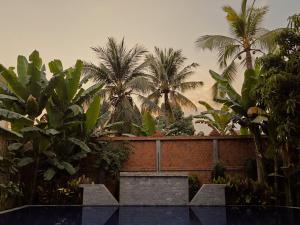 a garden with palm trees and a brick wall at Angkor Sand Hotel in Siem Reap