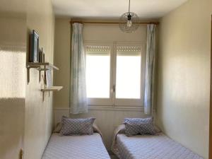 two beds in a room with a window at INNOUTHOME APARTAMENTO CON WIFI y AA_BALMES I in L'Ametlla de Mar