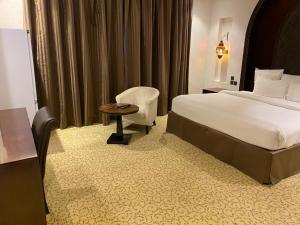 een hotelkamer met een bed en een stoel bij Ista Suites Seef in Manamah