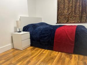 Schlafzimmer mit einem Bett mit einer roten und blauen Decke in der Unterkunft London Holiday Home in London