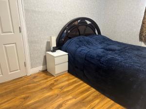 ein Schlafzimmer mit einem Bett mit einer blauen Decke und einem Nachttisch in der Unterkunft London Holiday Home in London
