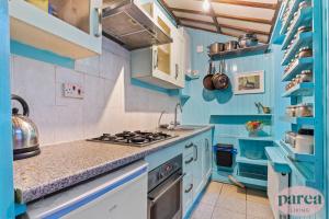 a blue kitchen with a stove and a sink at Parea Living - Cosy 1-Bed Artistic Flat at Newington Green in London