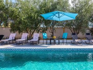 a pool with chairs and a table with an umbrella at Holiday Home Villa Vesna Lux in Zadar