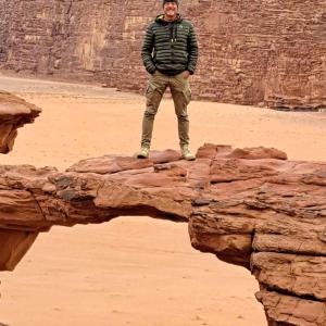 a man standing on a rock in the desert at Wadi Rum Nabatean Camp in Wadi Rum