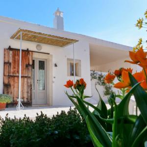 een wit huis met oranje bloemen ervoor bij Masseria Pezze Galere Piscina privata in Montalbano