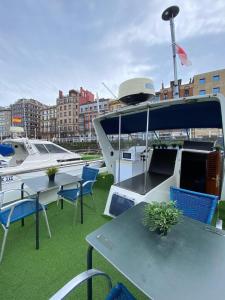 a table and chairs on a boat in a marina at Experiencia en el mar Gijon C in Gijón