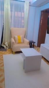 a living room with a white chair and a yellow pillow at L&A Homes in Kisii