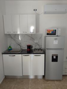 a kitchen with white cabinets and a stove and a microwave at Le petit Mimosa - City Center in Tataouine