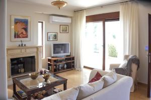 a living room with a white couch and a fireplace at Kiki’s 3BD apt. with Citrus Garden & BBQ in Gastoúni