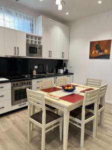 ベラトにあるApartment Villa Virginiaのテーブルと椅子のあるキッチンと白いキャビネットのあるキッチン