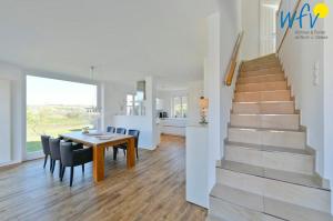 a dining room and kitchen with a table and a staircase at Landhaus Ostdüne Ferienwohnung Dünenmeer in Juist