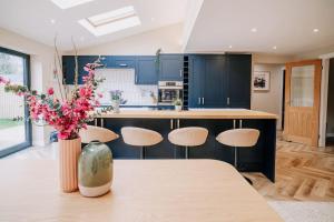 a kitchen with blue cabinets and a table with flowers at Modern Home in Warwickshire in Stratford-upon-Avon