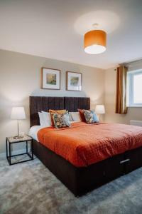 a bedroom with a large bed with orange sheets and pillows at Modern Home in Warwickshire in Stratford-upon-Avon