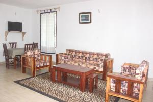 a living room with wooden furniture and a table at Gemini Villas in Kijiwetanga