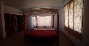 a bedroom with a bed with a canopy and a window at Gemini Villas in Kijiwetanga