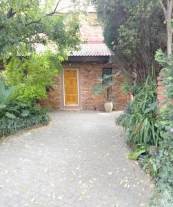 a brick house with a yellow door in a yard at Wapadrand Guest Suite in Pretoria