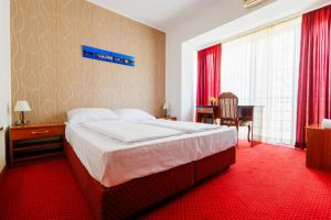 a bedroom with a large bed with a red carpet at Pansion Strossmayer in Osijek