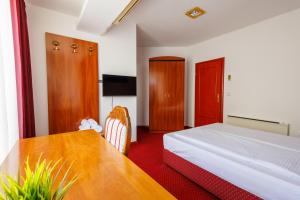 a hotel room with a bed and a table at Pansion Strossmayer in Osijek