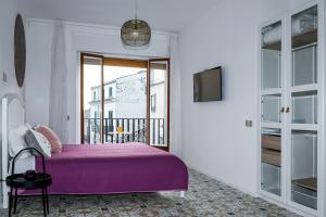 sypialnia z fioletowym łóżkiem i balkonem w obiekcie Edahouse w mieście Salerno
