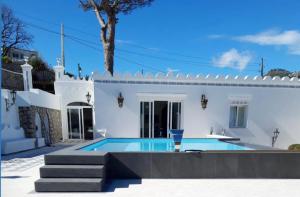 a swimming pool in front of a white house at Villa Raffaella in Capri