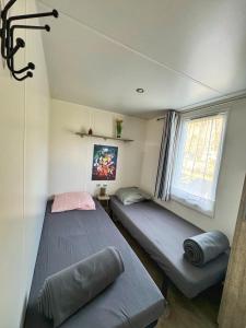 two beds in a small room with a window at Grand Mobile-Home 6 Places climatisé in Munster
