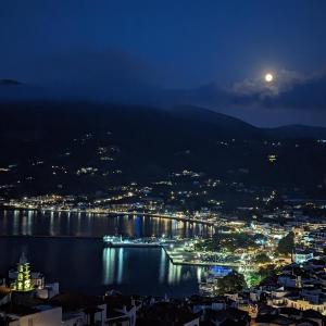 una vista de una ciudad por la noche con la luna en The Botanist Guesthouse, en Skopelos Town
