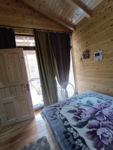 una camera da letto con un letto in una camera in legno con finestra di Wooden Mountain Villa a Berovo