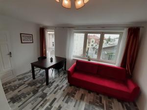a living room with a red couch and a table at Sopot Center Saba Appartement in Sopot