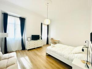 - une chambre blanche avec un lit et une télévision dans l'établissement Suites Larios, à Malaga