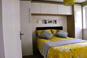 a bedroom with a bed with a yellow blanket at Ocean Breeze, Gower Holiday Village. Allows Dogs in Swansea
