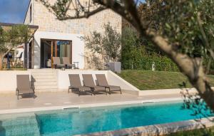een zwembad met stoelen naast een huis bij Villa-Veritas in Višnjan