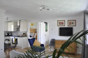 een woonkamer met een tv en een keuken bij Ocean Breeze, Gower Holiday Village. Allows Dogs in Swansea
