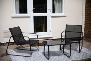 two black chairs and a table in front of a house at Probert- Perfectly Placed- Driveway - 3 bed in Wolverhampton