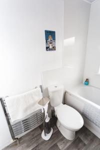 a white bathroom with a toilet and a bath tub at Probert- Perfectly Placed- Driveway - 3 bed in Wolverhampton