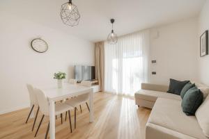 ein weißes Wohnzimmer mit einem Tisch und einem Sofa in der Unterkunft Resminik Home in Lido di Jesolo